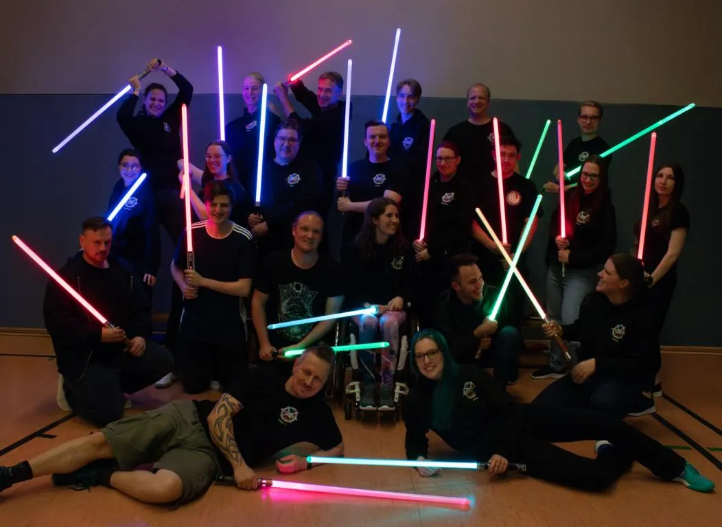 Die Mitglieder der Forcesabers stehen als Gruppe zusammen und haben Lichtschwerter in den Händen.