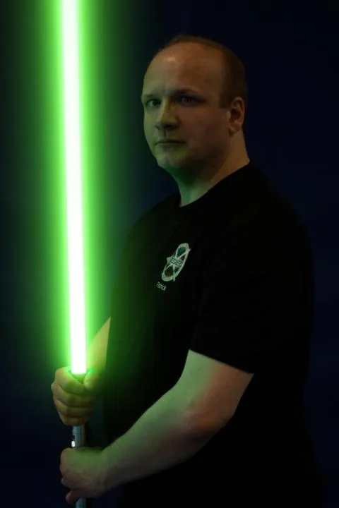 Portrait von Patrick mit einem Lichtschwert in der Hand.